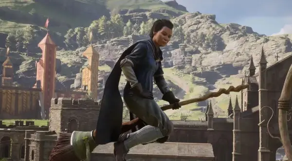 Gracz na miotle w grze Hogwarts Legacy Quidditch, lecący nad zamkiem i górami.