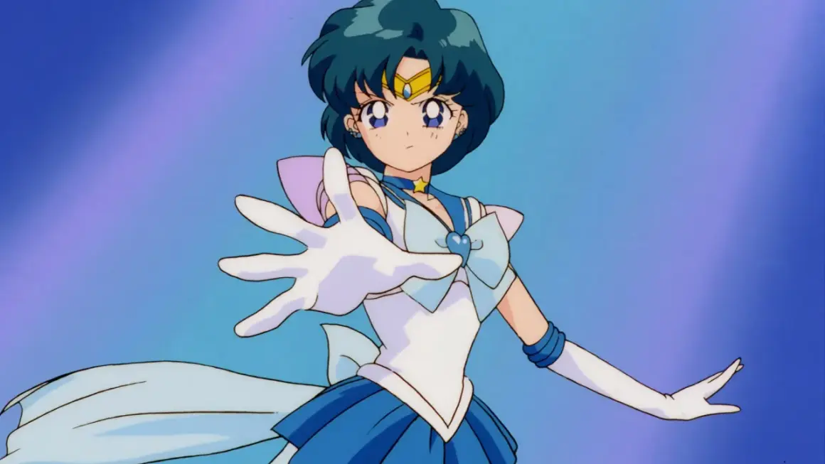 Sailor Mercury wyciąga rękę, gotowa do walki. Jej niebieskie włosy i strój podkreślają jej moc.