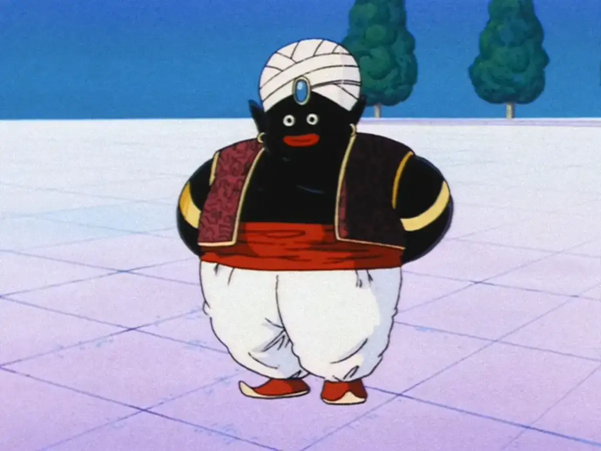 Mr Popo, w białym turbanie i czerwonym pasie, stoi na kwadratowej posadzce.