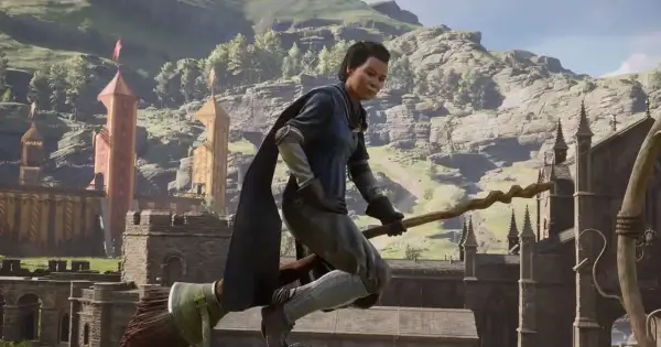 Gracz na miotle w grze Hogwarts Legacy Quidditch, lecący nad zamkiem i górami.